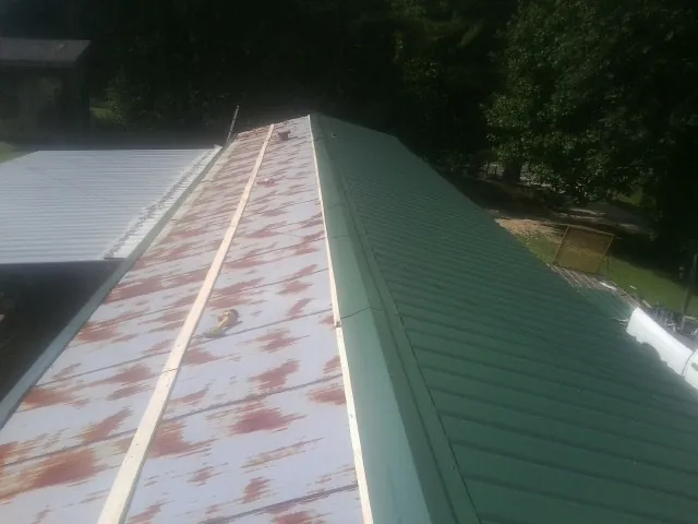 Old rusted panels beside newly installed green metal roofing — Wind Damage Roof Repair by Roofing Brothers in Mount Marion