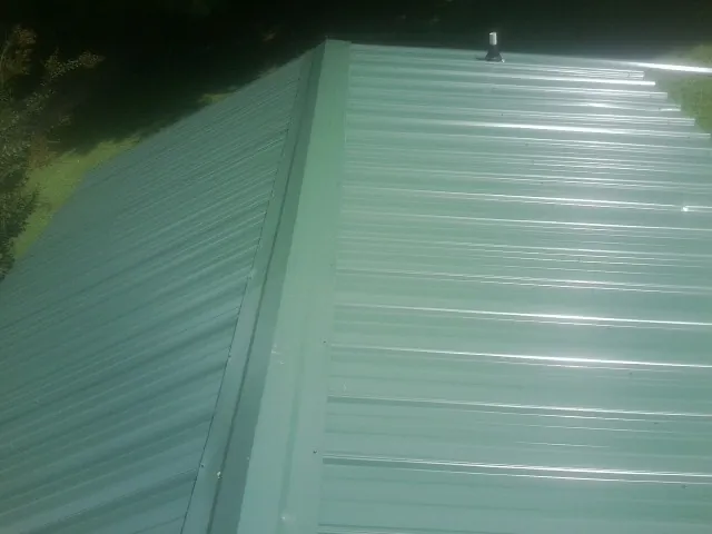 New green metal panels meeting at the ridge of a roof — Flat Roof Repair work by our crew in Mount Marion