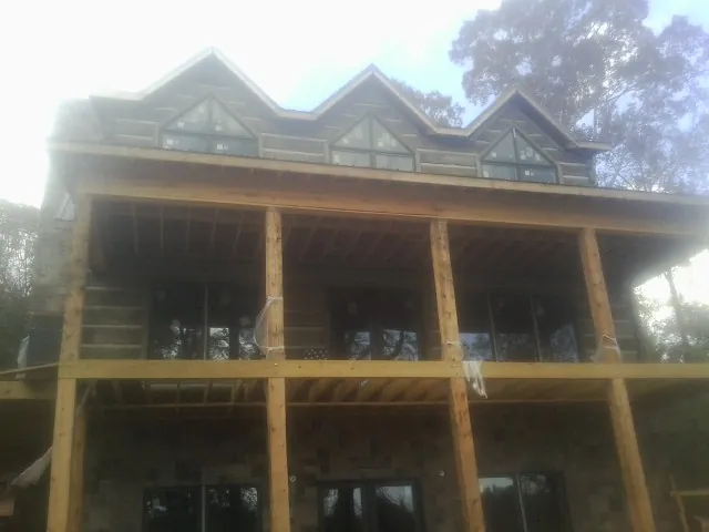 Dormers and porch framing on a large log home under construction — Roof Coating work by our crew in Mount Marion