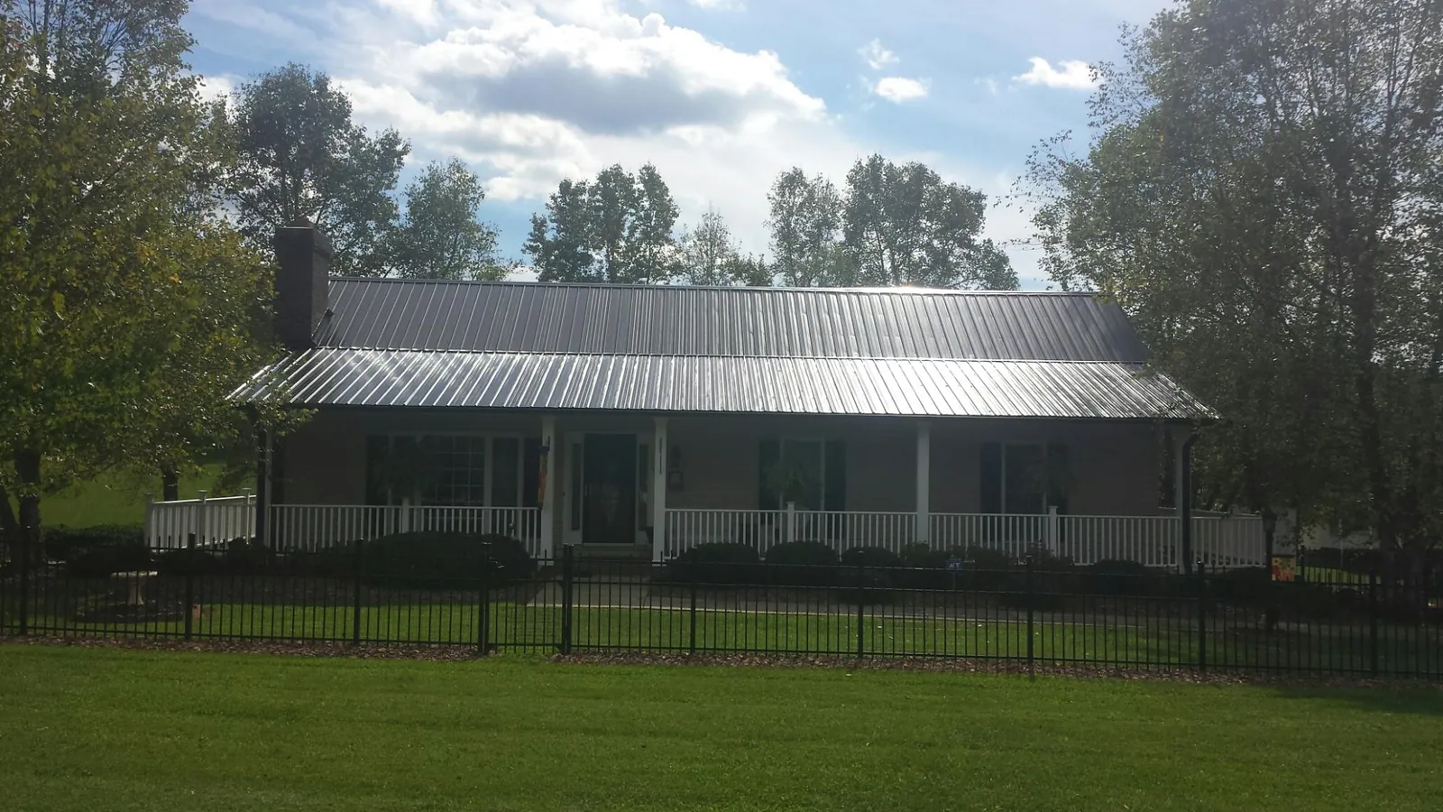 Gray metal roof on a brick ranch with a full width front porch — Gutter Guard Installation work by our crew in Mount Marion