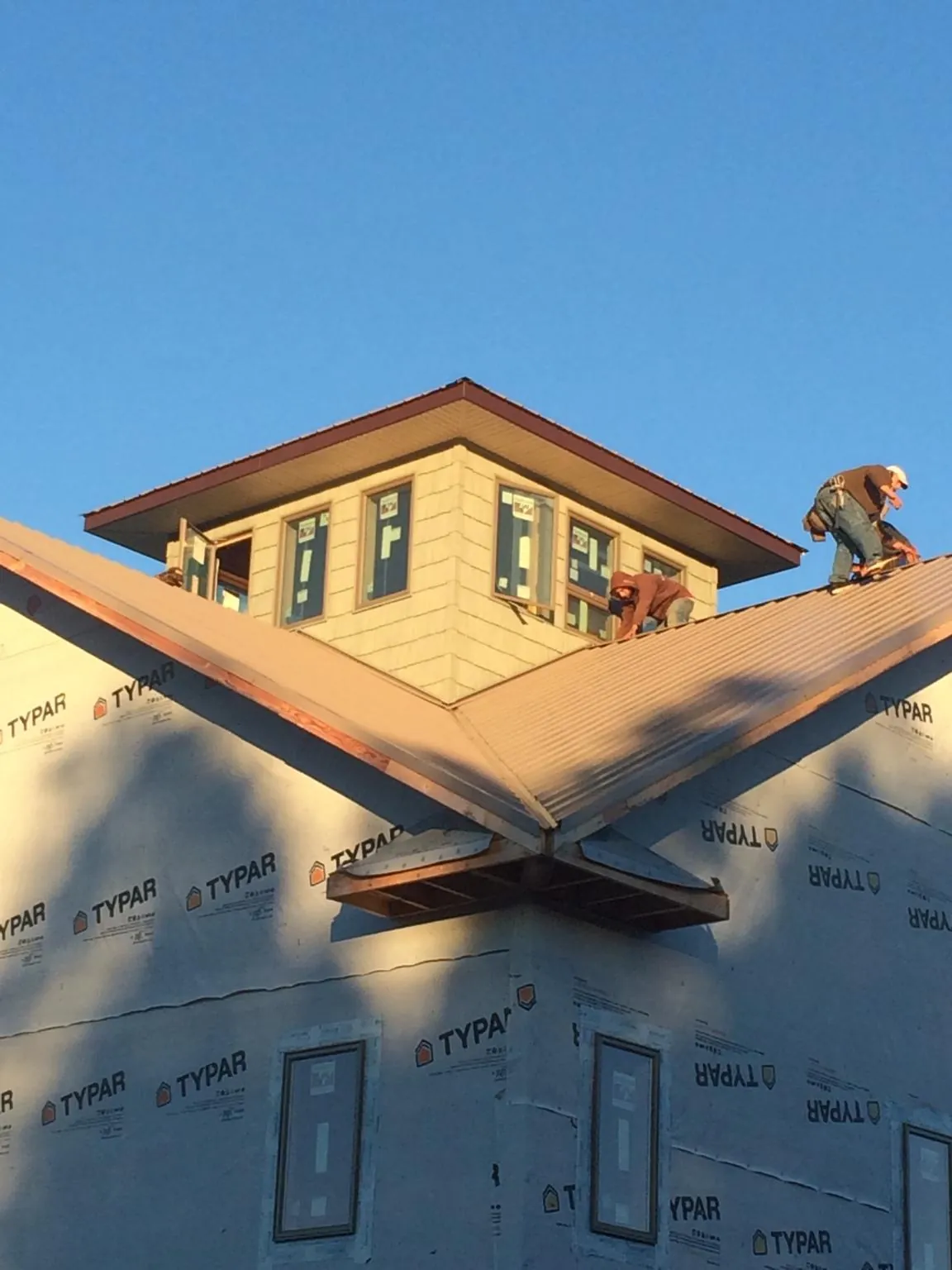 Roofers working around a rooftop cupola on a new metal roof at sunset — Roof Waterproofing in Mount Marion by Roofing Brothers